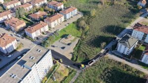 Alt metin: Kentsel bölgede apartmanlar, parklar ve doğal alanlar bir arada, ulaşım ve yaşam imkanlarıyla gelişmiş.